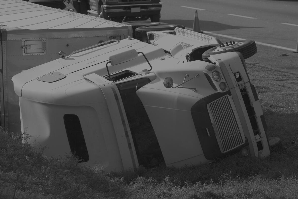 truck is laying on side of road after accident